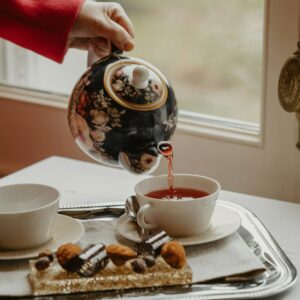 a person pouring tea into a cup on a tray