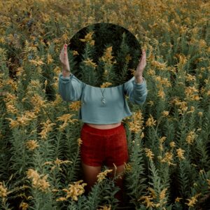 standing woman surrounded by yellow flower field during daytime