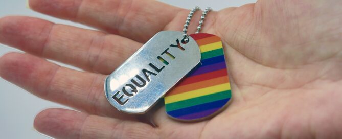 a person holding a rainbow dog tag in their hand